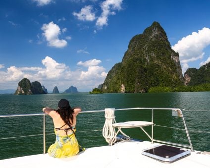 woman looking at mountain views from a boat on solo vacation