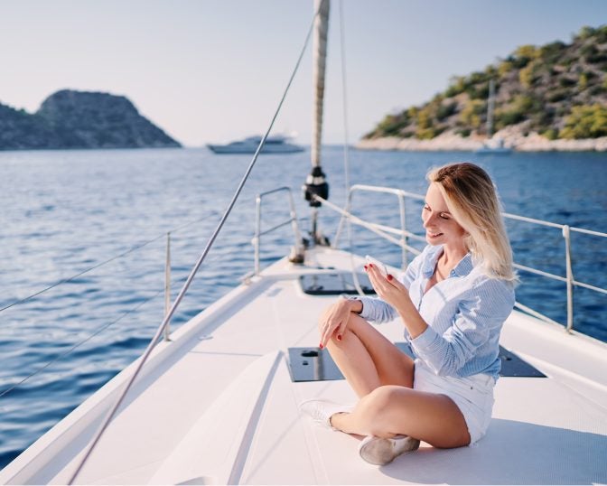 woman on boat looking at sailing apps